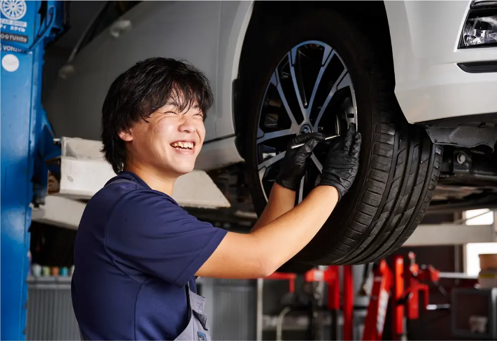 笑顔で車の整備をする男性の写真