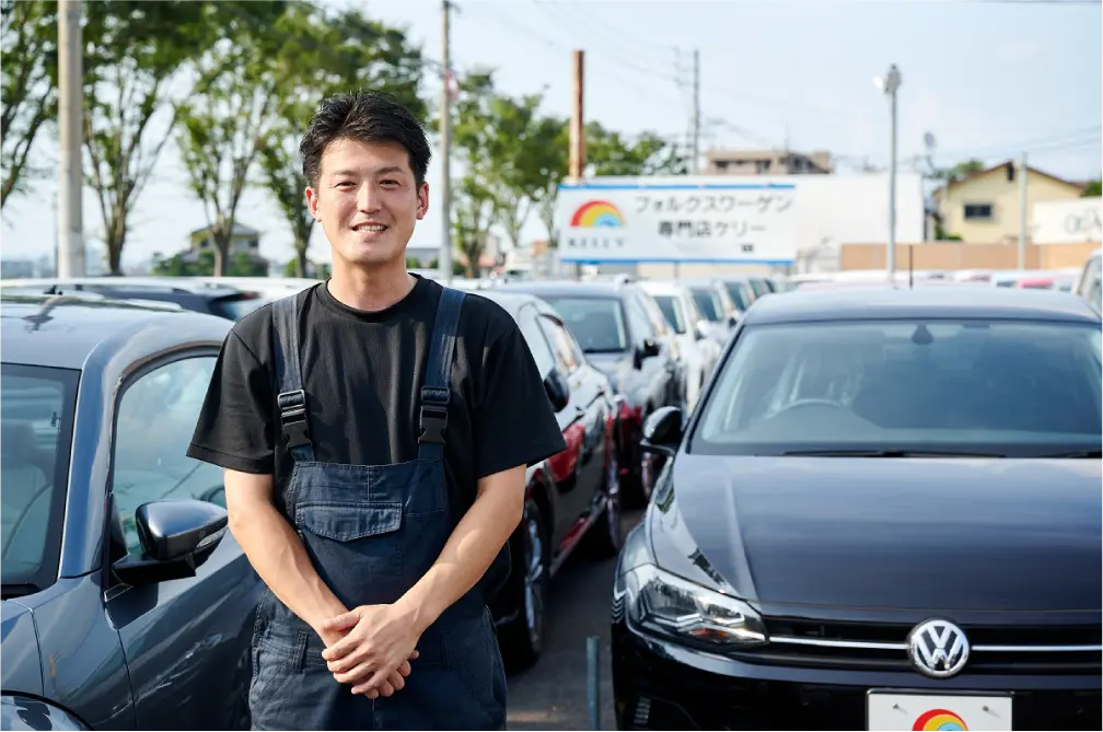 売り場の前で両手を前にして微笑む男性の写真