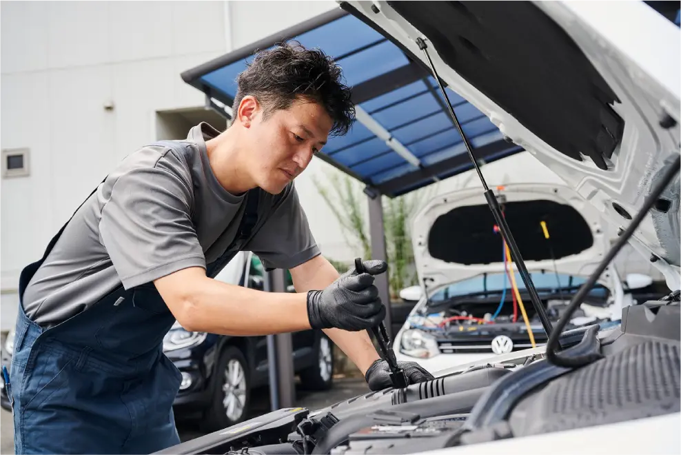 車のボンネットを開き、修理する男性の写真