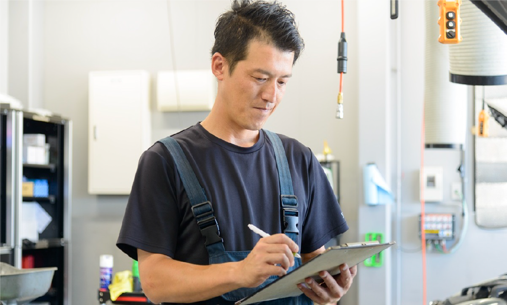 ペンを手にした職員がクリップボードの紙に書き込んでいる様子