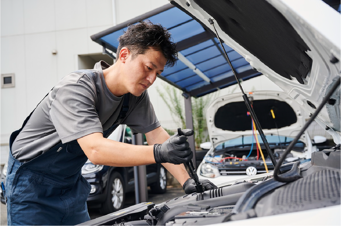 車のボンネットを開き、修理する男性の写真