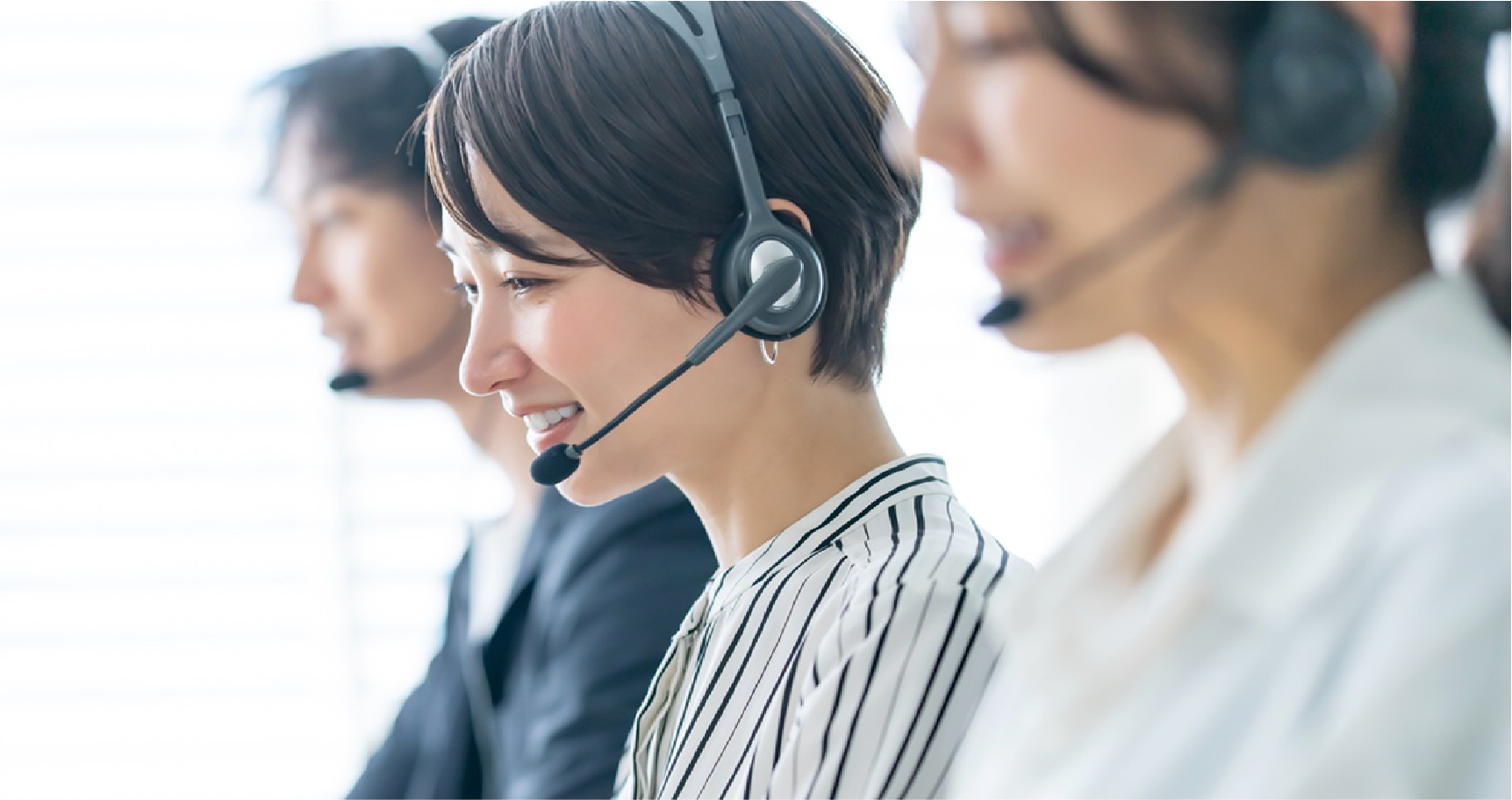 ヘッドセットをつけた女性が笑顔で連絡している写真